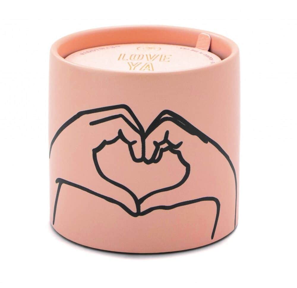 Pink ceramic candle with a heart design on the front, created by two hands forming a heart shape. This candle is made from Tobacco and Vanilla scented soy wax