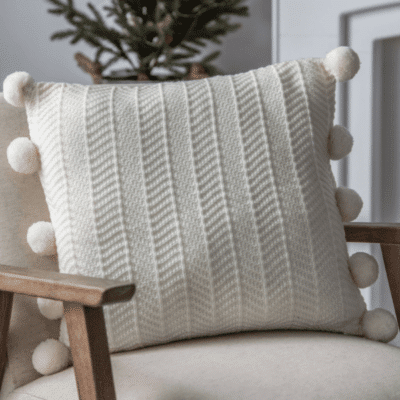 Herringbone cushion with pom pom details on an armchair